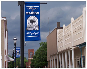 Picture of the town buildings. There is four light post with banners on them that say: "Welcome to Marion"
