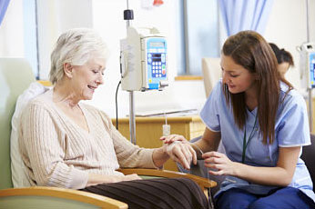 Picture of a young female Nurse putting an IV in an elderly patients hand. She is getting Infusion Therapy.