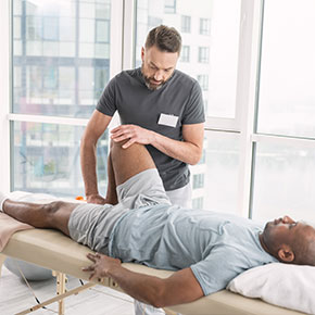 Picture of a male Occupational Therapist and a male Patient. The patient is lying down relaxing snd therapistThe occupational therapist will provide assistance to patients by contributing to their ability to perform their life roles in the occupations of work, self-care, and leisure.  The entire staff of therapists, assistants, aides, and clerical personnel is committed to excellence in all areas of rehabilitation.